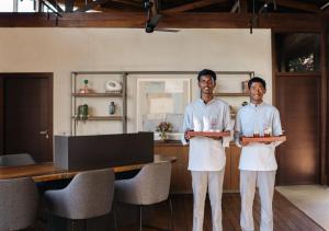 Zwei Männer in weißen Schürzen stehen in einem Raum in der Unterkunft LohonoStays Villa Amani 8B in Coonoor