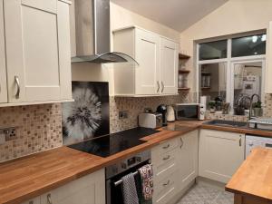 a kitchen with white cabinets and a stove top oven at Entire House, Parking, Facilities, sleeps up to 6, suitable for contractors, families or NHS in Liverpool