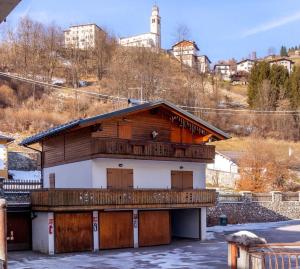 a house with wooden doors and a balcony at The Dolomites Lodge in San Pietro di Cadore