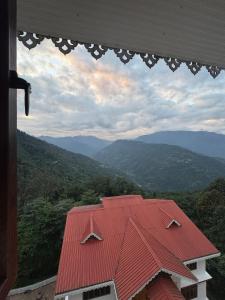 a red roof on a house with mountains in the background at DreamVilla Retreat Apartment Pelling in Pelling