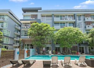 an apartment building with a swimming pool and chairs at Kris - Modern Spacious 2 Bedrooms Condo with Pool in Patong Beach
