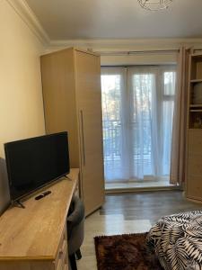 a room with a desk with a television and a bed at Bowery Apartment - 2 Bedrooms 1st floor in Dagenham
