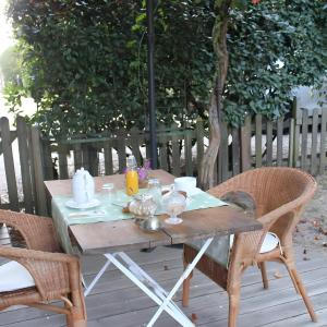 einen Holztisch auf einer Terrasse mit 2 Stühlen in der Unterkunft Le Clos Du Gorion - Chambre d'Hôte in Montussan