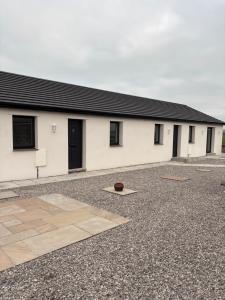 a white building with black doors and a courtyard at Cross Beck Cottage in Mawbray