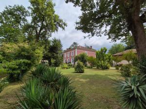 Manoir de Tireveste في Lesperon: بيت أحمر كبير مع ساحة مليئة بالنباتات