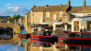 a group of boats docked on a river in front of buildings at Victoria Boutique Apartment in Skipton
