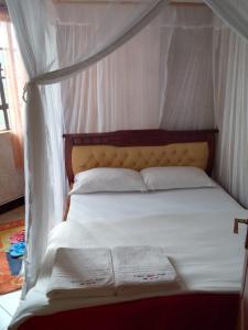 Un dormitorio con una cama con dosel con sábanas y almohadas blancas. en Oldoiyo Lengai Resort, en Karatina