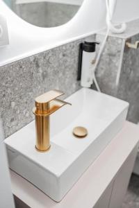 een witte wastafel met een koperen kraan bij HOME1 - Belvedere Boutique Hostel in Wenen
