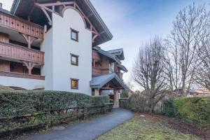 Ein weißes Gebäude mit einem Zaun neben einem Bürgersteig. in der Unterkunft Samoëns à Pied – Appt 4 pers in Samoëns