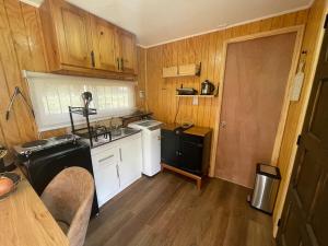 cocina con armarios de madera, fregadero y fogones en Cabaña moderna y equipada en parcela en Valdivia, en Valdivia