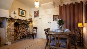 ein Esszimmer mit Tisch und Kamin in der Unterkunft Bell Cottage in Charlbury