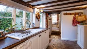 eine Küche mit Spüle und Fenster in der Unterkunft Bell Cottage in Charlbury + 17 Fotos