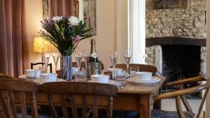 einen Holztisch mit einer Vase aus Blumen und Weingläsern in der Unterkunft Bell Cottage in Charlbury