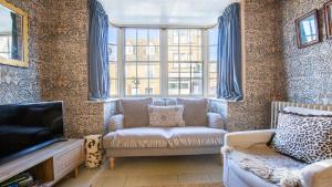 ein Wohnzimmer mit Sofa und Fernseher in der Unterkunft Bell Cottage in Charlbury