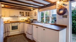 a kitchen with white cabinets and a sink at Bell Cottage in Charlbury +15 photos