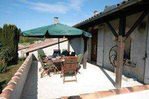a table and chairs under a green umbrella on a patio at Maison De Lafenestre in Saint-Maigrin
