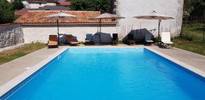 a blue swimming pool with chairs and umbrellas at Maison De Lafenestre in Saint-Maigrin