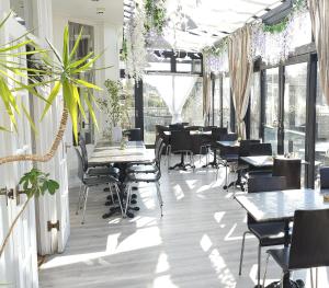 a restaurant with tables and chairs and plants at Dukes Folly Hotel in Southport