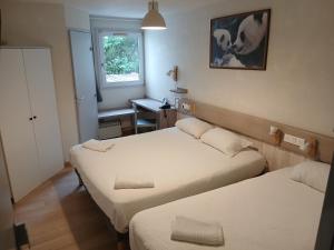 ein Zimmer mit zwei Betten, einem Schreibtisch und einem Fenster in der Unterkunft Logis Hôtel Come Inn in Poitiers + 31 Fotos