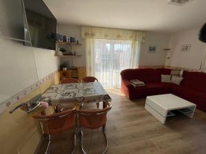 a living room with a table and a red couch at Fewo Anders Nr1 in Neue Tiefe Fehmarn