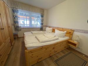 a bedroom with a wooden bed with white sheets at Fewo Anders Nr1 in Neue Tiefe Fehmarn