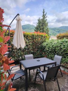 un tavolo, sedie e un ombrellone in un patio di Photo House Collodi La Villetta a Collodi