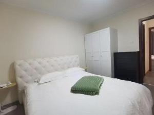 ein Schlafzimmer mit einem weißen Bett und einem grünen Kissen darauf in der Unterkunft Shoucheng international 2104 in Peking