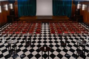 伊斯坦布尔Soho House Istanbul的一个空荡荡的礼堂，红色椅子摆放在方格地板上。