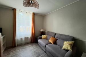 a living room with a gray couch and a window at Escapade à Éguzon Maison 3 chambres in Éguzon-Chantôme