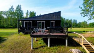 a small black house with a dock in a field at HOLIDAY CABIN 'CRANE' with a private hot-tub and sauna extra fee in Avotkalni