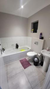 a bathroom with a tub and a toilet and a sink at The best uptown experience in the windy city in Gqeberha