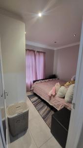 a bedroom with a bed with pink sheets and pillows at The best uptown experience in the windy city in Gqeberha
