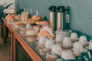Una mesa larga llena de platos, tazas y fuentes. en Pousada Ebenézer de Cordeiro rj, en Cordeiro
