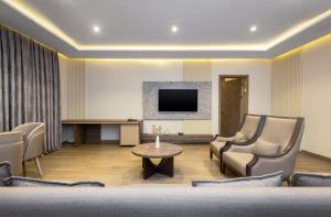 a living room with chairs and a table and a tv at CheckInn Garki, Abuja in Abuja