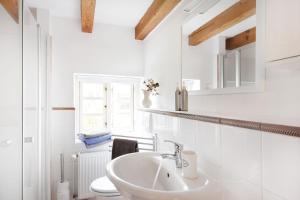 a white bathroom with a sink and a toilet at Kembser Cottage - Ostholstein - NEU! in Behrensdorf +32 photos