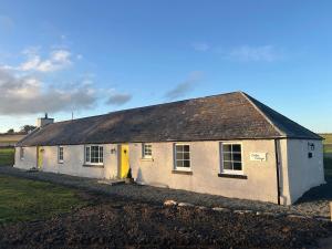 a white house with a yellow door in a field at Calsie Cottage, Clatt in Kirktown of Clatt