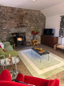 een woonkamer met een stenen muur en een open haard bij Calsie Cottage, Clatt in Kirktown of Clatt