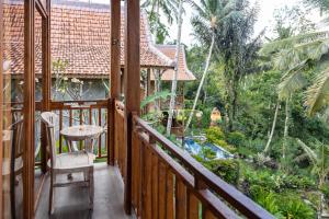 a balcony of a house with a table and a chair at Kawiya Healing Retreat Sanctuary in Tampaksiring +24 photos
