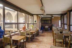 a dining room with tables and chairs and windows at Auberge Ayam Atlas- pool 10mn away in Ourika