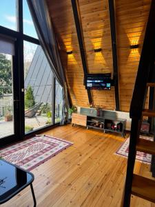 a living room with wooden floors and a large window at Cottage Sataplia in Kutaisi