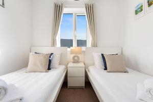 two beds in a room with two windows at Rigg & Rest Apartment - Bowness in Bowness-on-Windermere