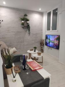 Una sala de estar con un sofá y un televisor. en Caleta Dreams. Apartamento a estrenar. A 60 metros Playa, en Cádiz