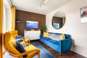 a living room with a blue couch and yellow chairs at Rigg & Rest Apartment - Bowness in Bowness-on-Windermere