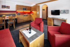 ein Wohnzimmer mit roten Stühlen und einem Tisch mit einer Flasche Wein in der Unterkunft Appartement Désirée inkl der SUPER SOMMER CARD im SOMMER 2025 in Serfaus