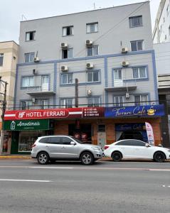Dos coches aparcados delante de un edificio en Hotel Ferrari, en Rio do Sul