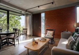 ein Wohnzimmer mit einer Ziegelwand und einem Tisch in der Unterkunft LohonoStays Amani Villa 9A in Coonoor + 30 Fotos
