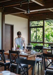 Ein Mann steht an einem Tisch in einem Restaurant. in der Unterkunft LohonoStays Amani Villa 9A in Coonoor