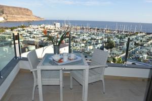 a table and chairs on a balcony with a view of a harbor at Sunset Puerto de Mogan in Puerto de Mogán