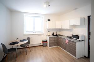 Una cocina con gabinetes blancos y una mesa y sillas. en Apartmány Stdaniela, en Bohumín