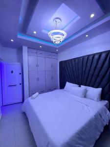 Un dormitorio con una gran cama blanca y una luz azul en Fola Homes, en Suru Lere